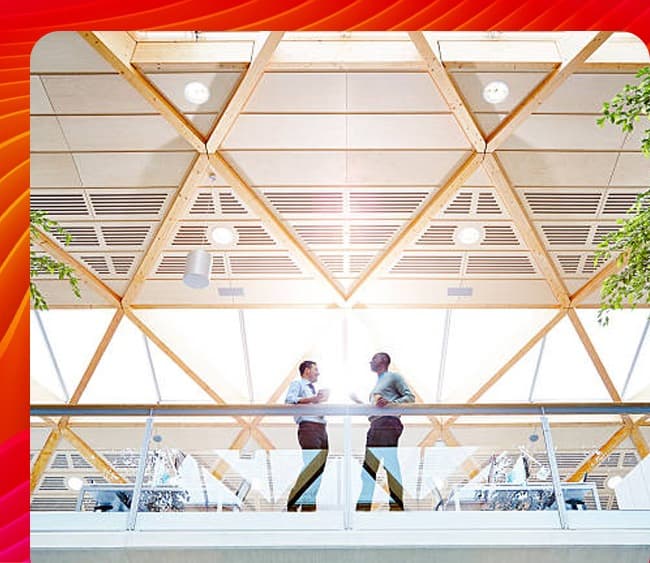 Two colleagues discussing business on a balcony overlooking a modern office space.